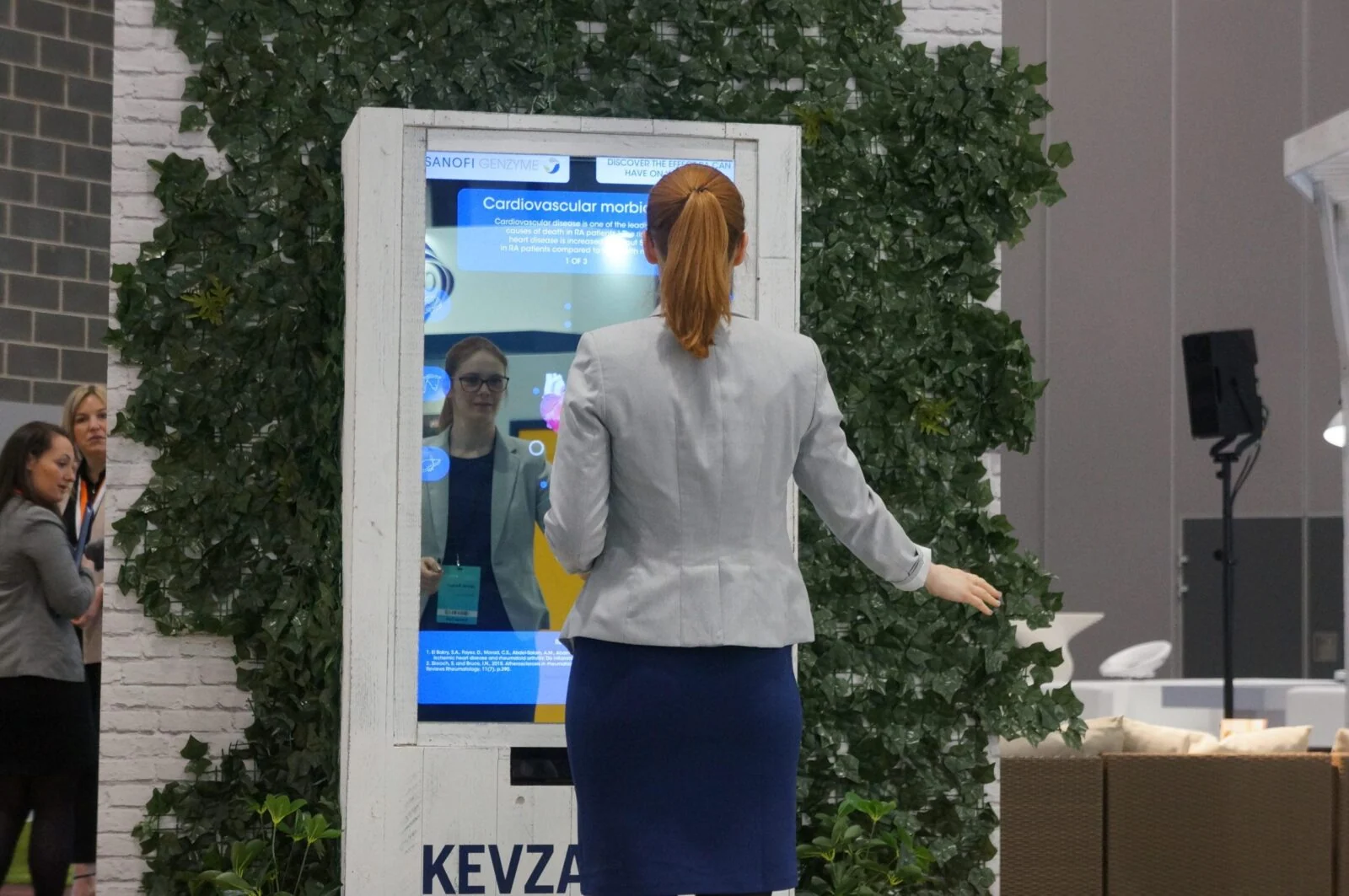 Zwiedzający z rozłożonymi rękami przed interaktywnym lustrem rentgenowskim na wystawie.