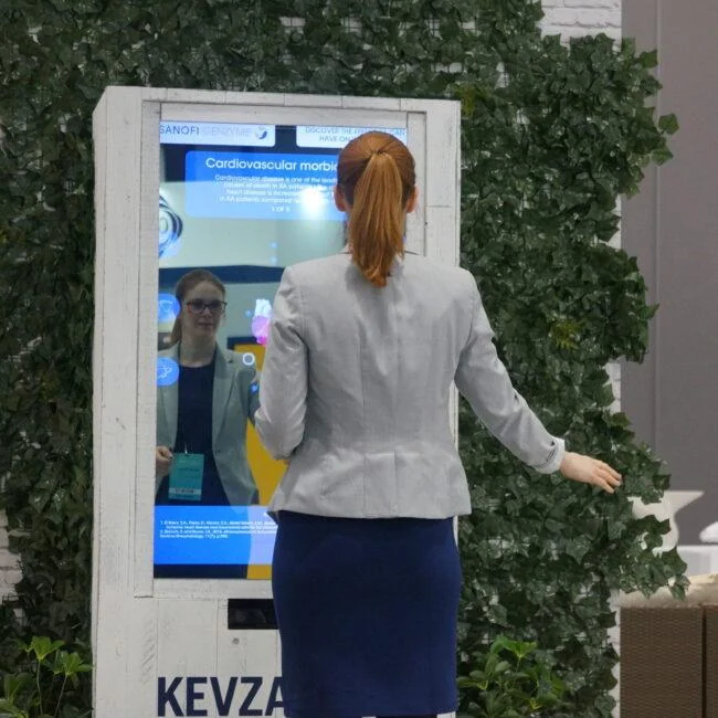 Zwiedzający z rozłożonymi rękami przed interaktywnym lustrem rentgenowskim na wystawie.