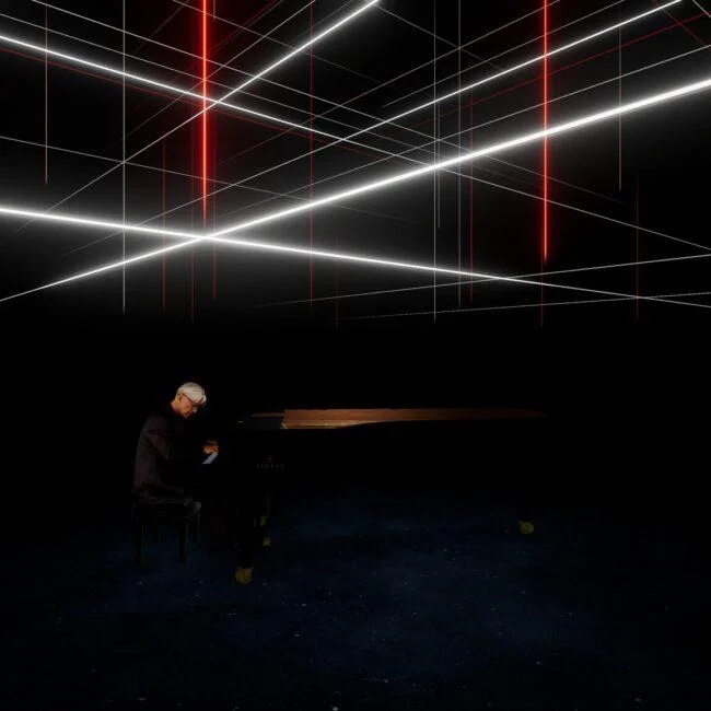Pianista przy fortepianie pod przecinającymi się białymi i czerwonymi liniami światła w Kagami.