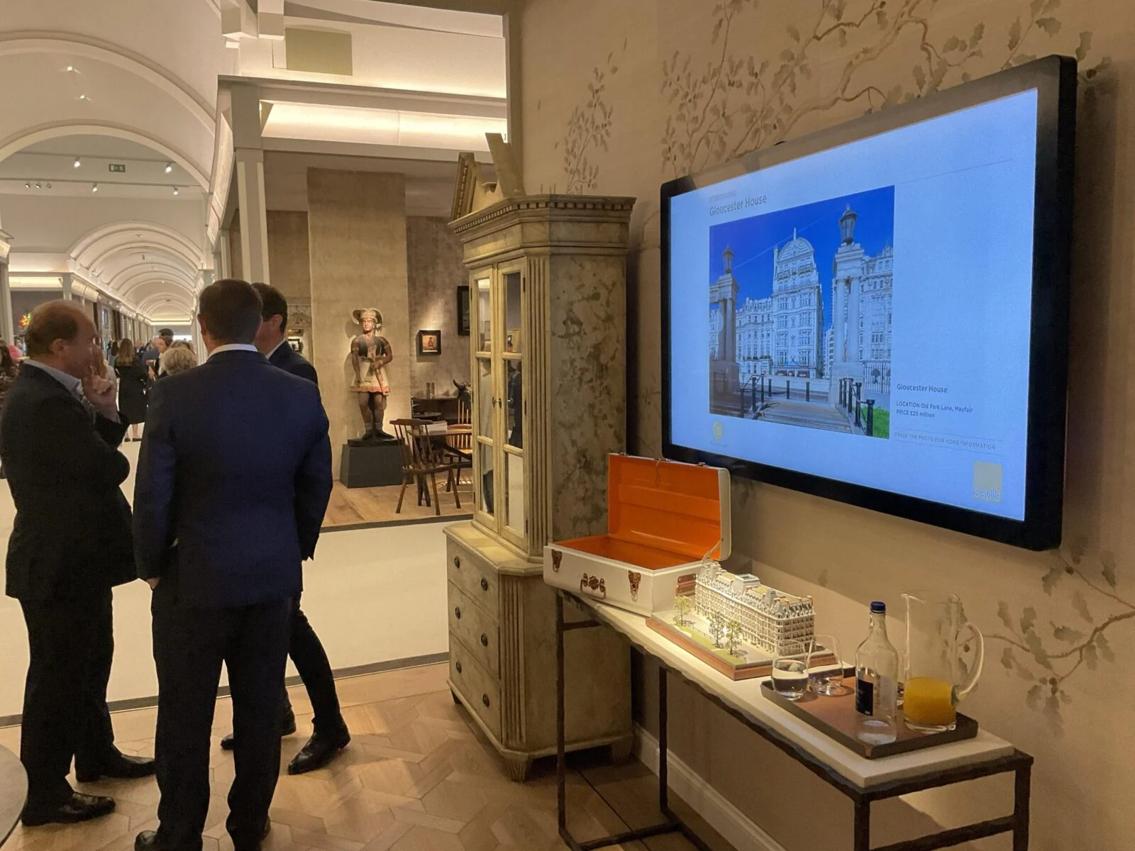 Zwiedzający obok ekranu z architekturą i makiet na Masterpiece Fair.
