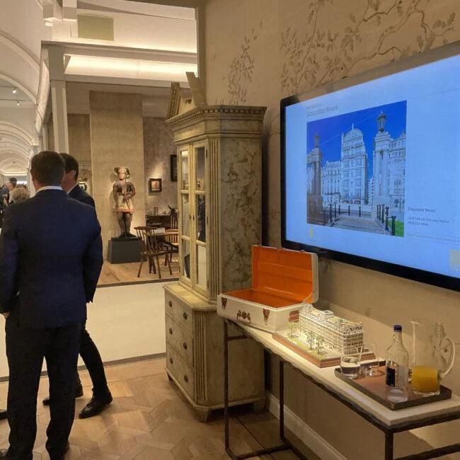Zwiedzający obok ekranu z architekturą i makiet na Masterpiece Fair.