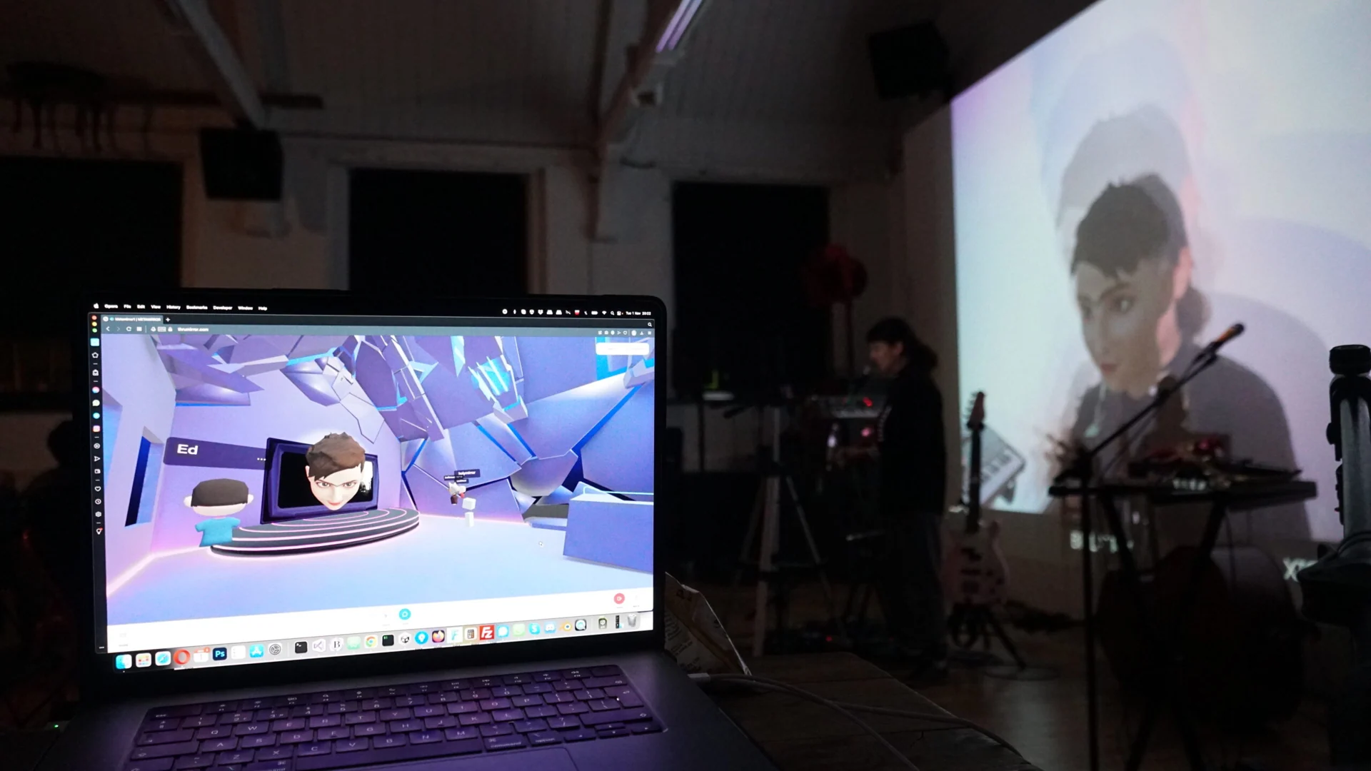 Laptop pokazuje wirtualną przestrzeń Metamirror obok muzyka na żywo i wyświetlanego awatara.