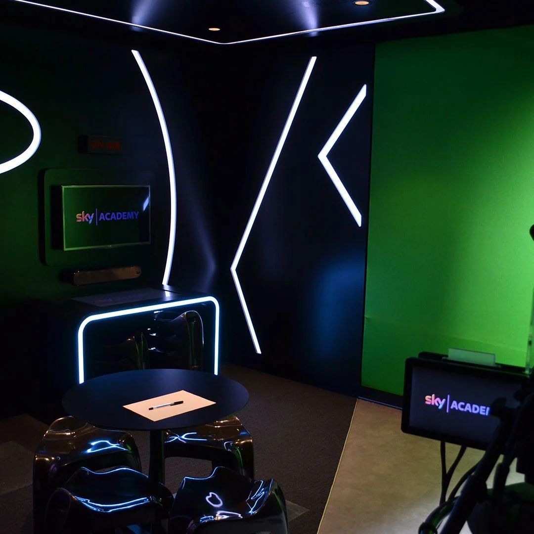 Studio telewizyjne z green screenem, kamerami i białymi pasami LED.