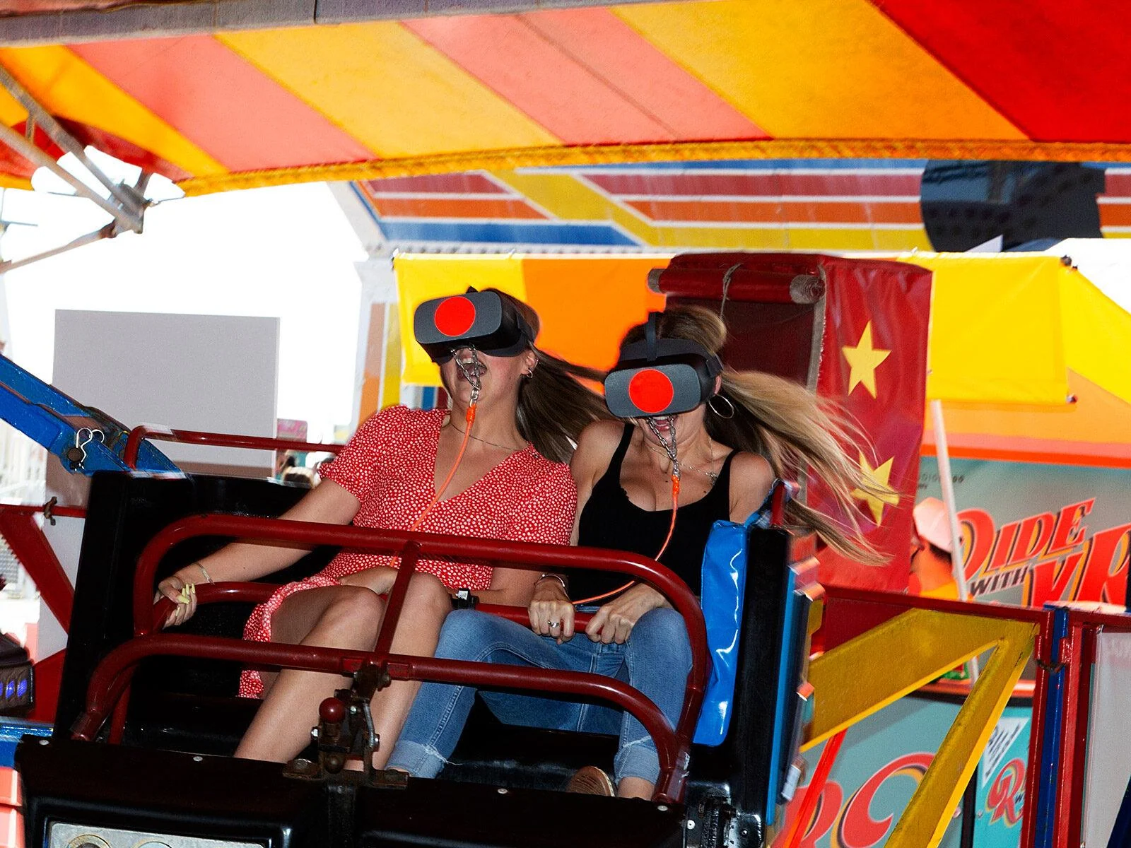 Dwoje pasażerów w goglach VR na karuzeli Twister na molo w Brighton.