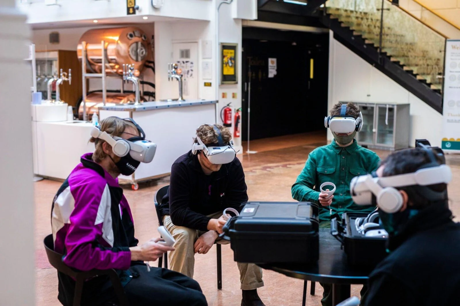 Czworo uczestników w goglach VR, z kontrolerami, przy stole.