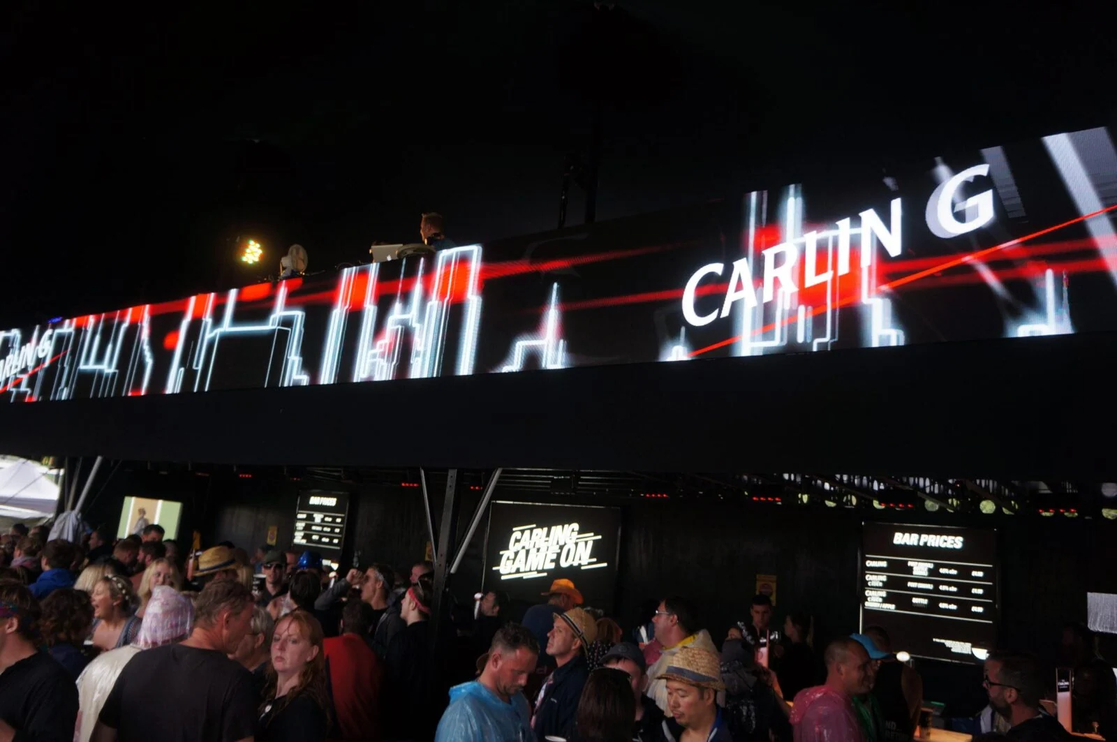 Animowane grafiki świetlne Carling nad zatłoczonym barem festiwalowym.
