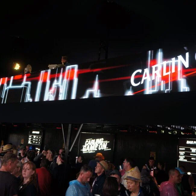 Czerwono-białe wizualizacje Carling na długim ekranie nad uczestnikami festiwalu.