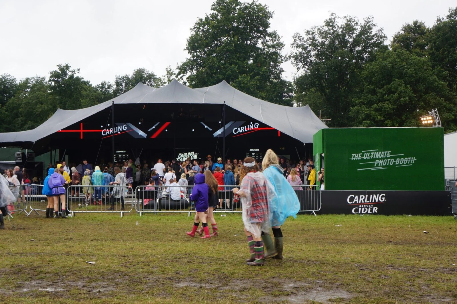 Namiot festiwalowy Carling z tłumem na zewnątrz i zielonymi oznaczeniami cydru.