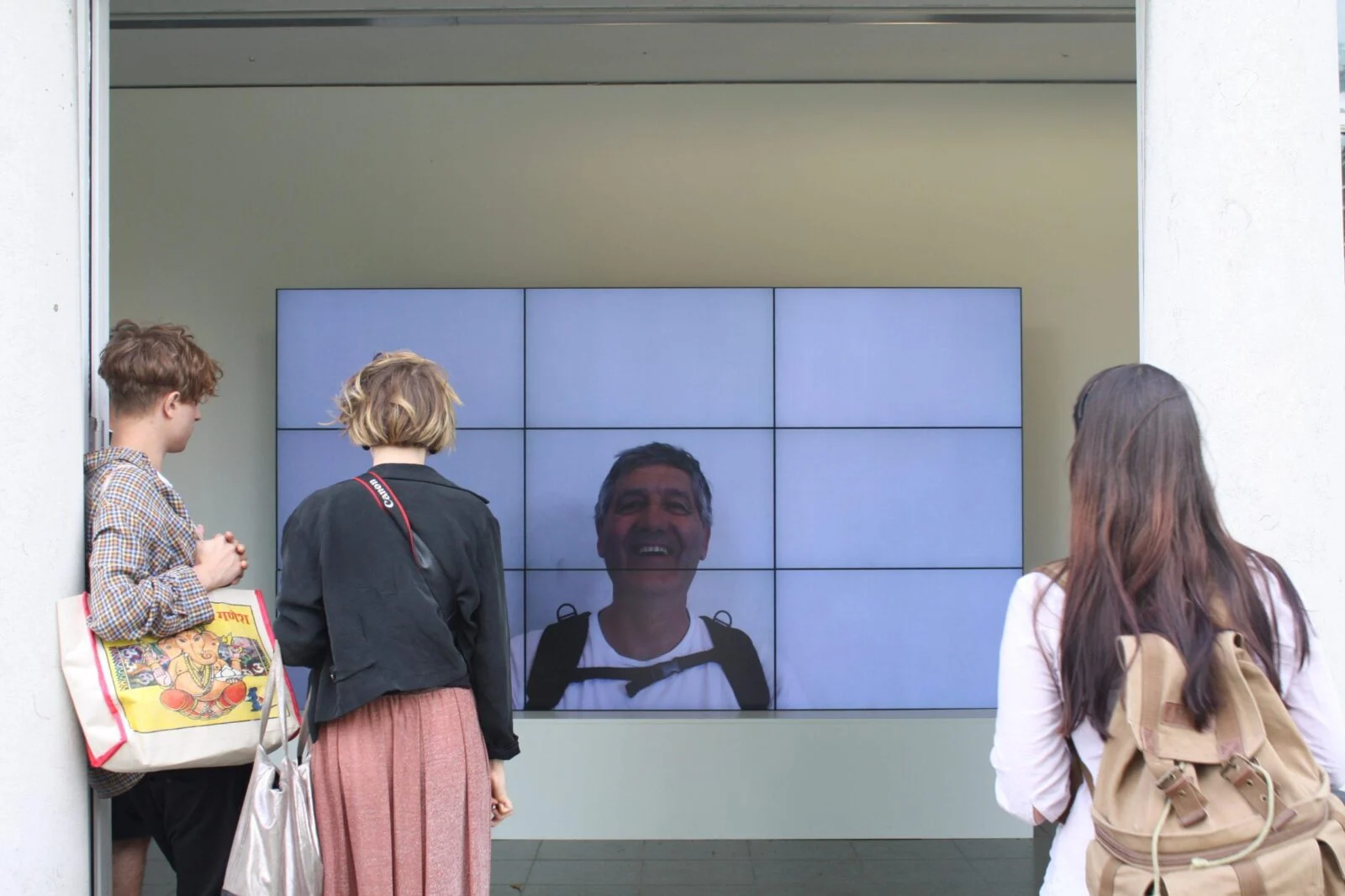 Zwiedzający oglądają uśmiechniętą twarz na ścianie wideo Smiles Film.